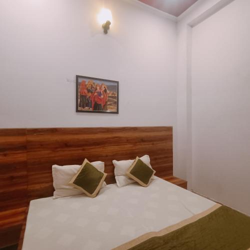 a bedroom with a white bed with a wooden headboard at hotel Atithii in Rīngas