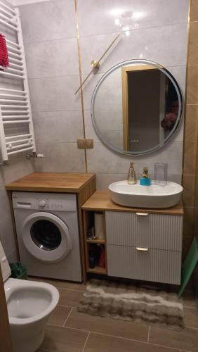 a bathroom with a sink and a washing machine at Major Apartment in Dziwnów
