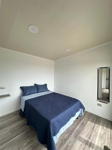 a bedroom with a blue bed and a mirror at Tordos Lodge in Quintero