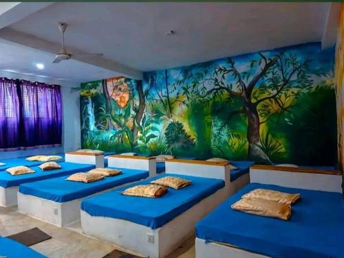 a room with four beds in front of a mural at Happy Laugh Ella in Ella