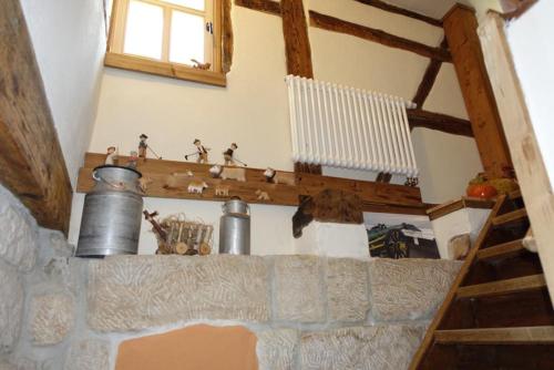 a room with a stone fireplace with metal pots on a shelf at Gohrischer Hof Anno 1798 in Kurort Gohrisch