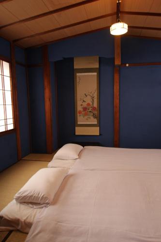 um quarto azul com uma cama grande e almofadas brancas em Guest House Ui-ca em Kanazawa
