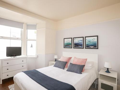 a white bedroom with a bed and a tv at Angorfa Apartment in Pwllheli