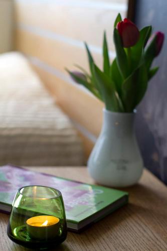 a candle in a glass next to a vase with flowers at Hotell City in Härnösand