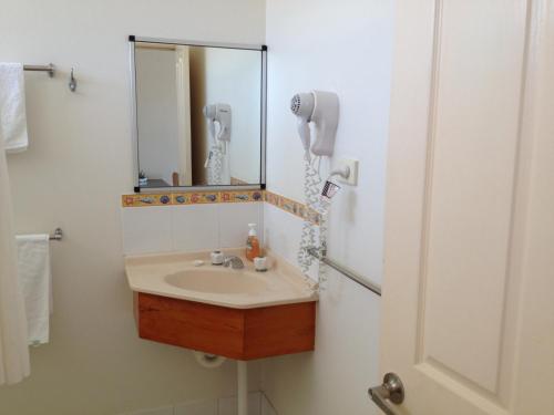 ein Bad mit einem Waschbecken und einem Spiegel in der Unterkunft Shell Motel (Pearly Shell Motel) in Bowen