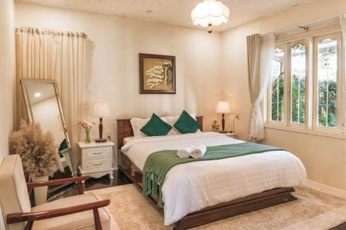 a bedroom with a bed and a mirror and a chair at Nostalgia Villa Dalat in Ấp Ða Lợi