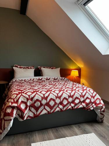 a bedroom with a bed with a red and white comforter at Bel appartement 2 pièces in Soufflenheim