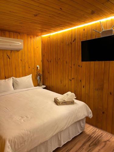 a bedroom with a white bed and a flat screen tv at NATU Visconde de Mauá in Itatiaia
