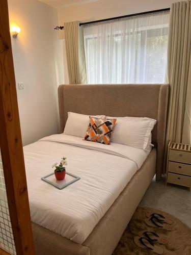 a bed with a tray with a plant on it at Ems Haven Apartment in Ongata Rongai 