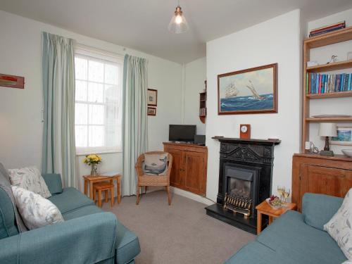 a living room with two blue couches and a fireplace at Tillerman Cottage Appledore Devon in Appledore