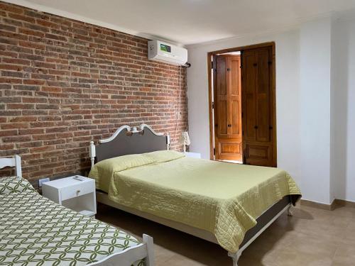 a bedroom with two beds and a brick wall at La Esquina en el Rio in Paraná
