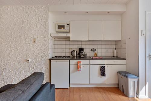 a kitchen with white cabinets and a couch in a room at Geuldal Guest Apartments in Valkenburg