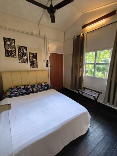 a bedroom with a large white bed and a window at Blissful Garden Chalet Langkawi in Pantai Cenang