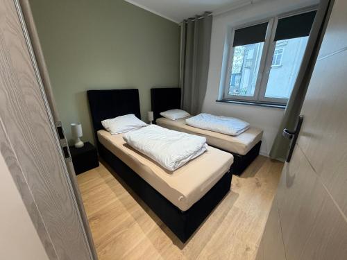 two beds in a small room with a window at Duży Apartament 3 pokoje Park City in Ostrów Wielkopolski