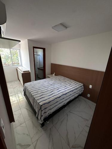 a bedroom with a bed with a striped comforter at Village com 2 suites com ar a 300mts da praia e do rio in Mata de Sao Joao