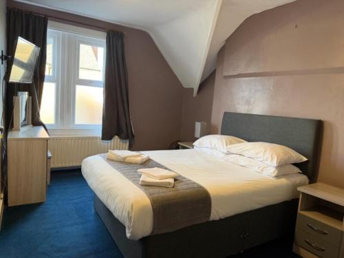 a bedroom with a large bed with towels on it at The Avenue Hotel in Grantham