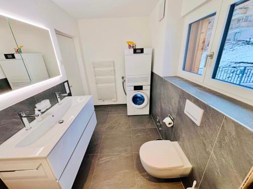 a bathroom with a toilet and a sink and a washing machine at Brand-New Eiger View 3BR Apartment - Premium Location - Free Parking - Terrace in Grindelwald