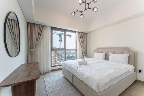 a white bedroom with a large bed and a mirror at HAVN - 1 bedroom in Madinat Jumeirah Living in Dubai