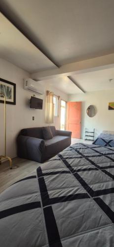 a bedroom with a bed and a couch at Lolas House in Ensenada