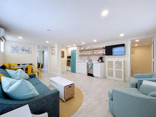 a living room with two blue couches and a kitchen at Sea LaVie!! Steps 2 Beach & Bay in Bradenton Beach