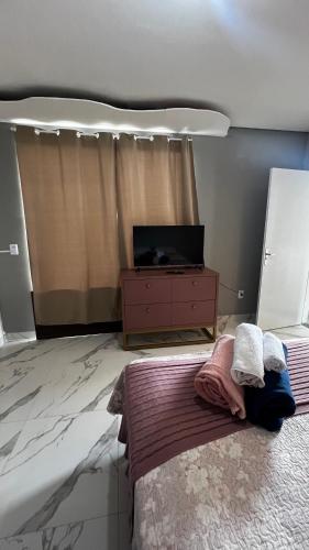 a bedroom with a bed and a dresser with a television at Studio no Centro da Cidade in Parauapebas