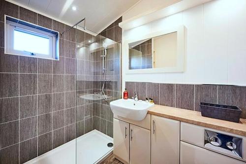a bathroom with a sink and a mirror and a shower at Finest Retreats - Silverwood Hideaway Lodge in Errol
