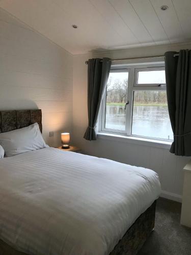 a bedroom with a large bed and a window at Finest Retreats - Silverwood Hideaway Lodge in Errol