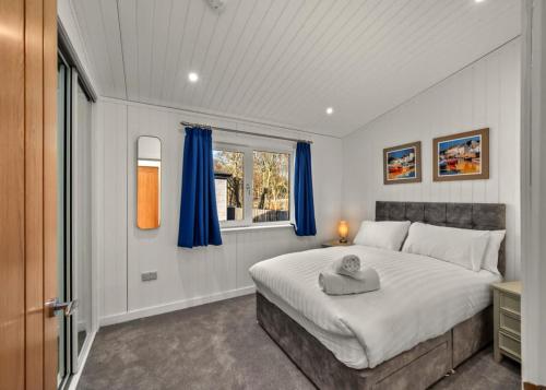 a bedroom with a large bed with blue curtains at Finest Retreats - Silverwood Deluxe Chalet in Errol