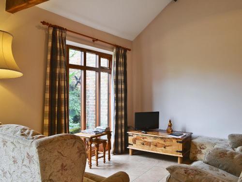 ein Wohnzimmer mit Sofa und Schreibtisch mit Fernseher in der Unterkunft Oregano - E4483 in Catfield