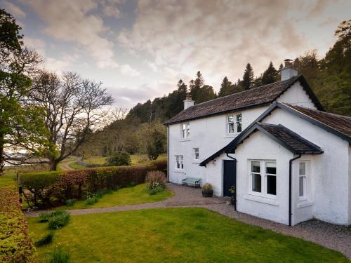 a white house in a yard with a driveway at Cliff Cottage in Port Appin