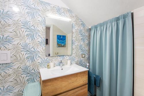 a bathroom with a sink and a blue shower curtain at CasAmica by BarbarHouse in Vieste