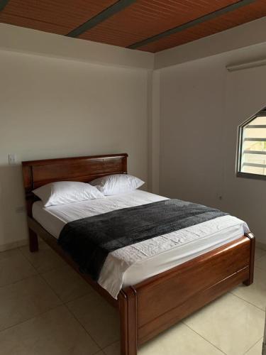 a bedroom with a bed with a wooden headboard at Hospedaje Villa Laura in Cite