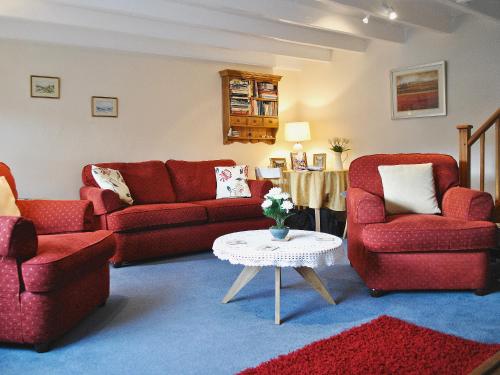 a living room with red furniture and a table at Sunnyside in Sandsend