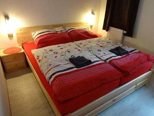 a bedroom with a bed with red comforter and black shoes on it at Moderni Domek Lipno in Lipno nad Vltavou