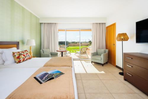 a hotel room with a large bed and a television at Pestana Alvor Beach Villas Seaside Resort in Alvor