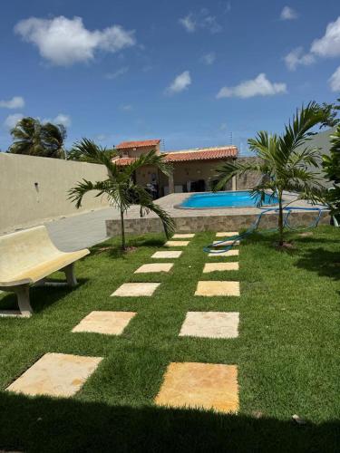 a grassy yard with a bench and a house at Espaço Recanto Del Mar in Paracuru