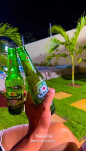 a person holding two green bottles of beer at Espaço Recanto Del Mar in Paracuru