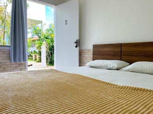 a bedroom with a large bed with a wooden headboard at IBELLO BEACH Pousada in Cabo Frio
