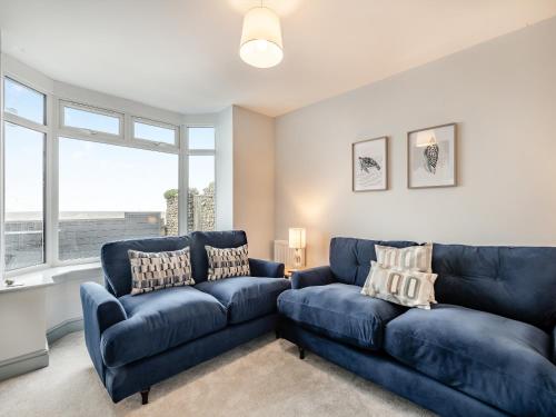 a living room with two blue couches and a window at Stones Throw Cottage in Sheringham