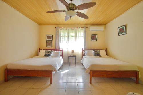 two beds in a room with a ceiling fan at Hotel Sol y Mar in Santa Catalina