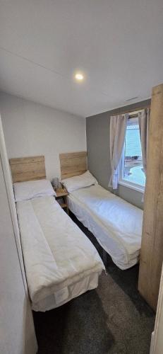 two beds in a room with a window at 8 berth 3 Bedroomed CARAVAN Lyons Robin Hood Rhyl 17 Elm Crescent in Meliden