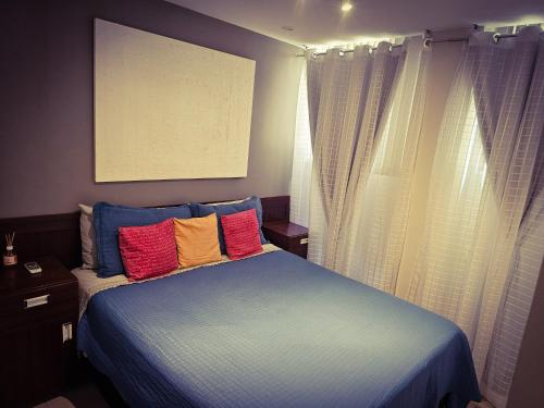 a bedroom with a blue bed with colorful pillows at 2 BEDROOM Condo -IPANEMA in Rio de Janeiro