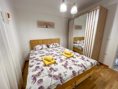 a bedroom with a bed with yellow towels on it at Apartman Wish Lux in Vrnjci