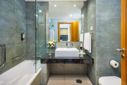 a bathroom with a sink and a tub and a toilet at Pestana Alvor Beach Villas Seaside Resort in Alvor