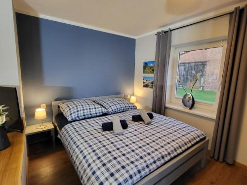 a bedroom with a bed with a plaid blanket and a window at 15 Vogelnest - Hof Wiesengrund in Parchtitz