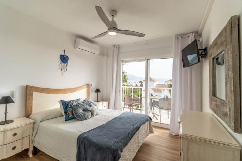 a bedroom with a bed with a ceiling fan and a balcony at RentitSpain - Nerja - Apartamentos Vistas Únicas al Mar Mediterráneo in Nerja