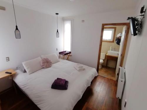 a bedroom with a white bed with a pink bow on it at Espacio Innata in Punta Arenas