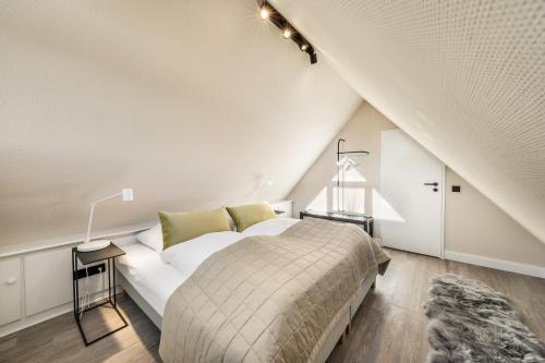 a white bedroom with a bed in a attic at Mare in Hörnum