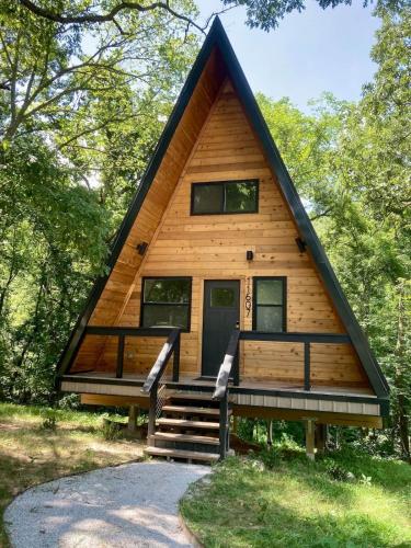 a cabin in the woods with a black roof at Black Walnut Bungalow-Cozy Forest A-frame near Bentonville in Rogers