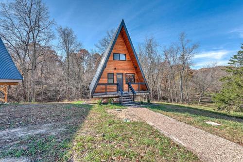 a small house with a triangular roof on a field at Dogwood Den- Cozy Forest A-Frame Near Bentonville in Rogers